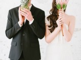 a bride holding a large bloom and a groom holding a pineapple remind that their wedding is a tropical one