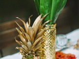 a gilded pineapple and a gold vase with tropical leaves is a chic and refined glam wedding centerpiece for a modern wedding