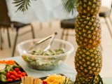 a berry and fruit table decorated with a pineapple tree – lots of pineapples stacked and topped with leaves is ideal