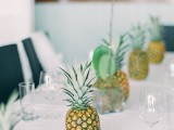 a minimalist tropical wedding tablescape with pineapples, orchids and all white everything is very chic