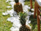 pineapples lining up the aisle and white tropical blooms are ideal to accent a wedding ceremony space