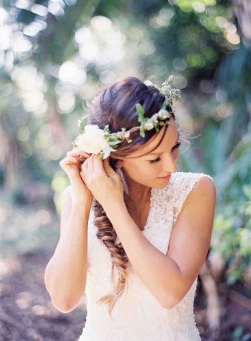 a messy twisted side braid with a volume on top and a neutral flower crown with greenery is a great idea for a spring or summer boho bride