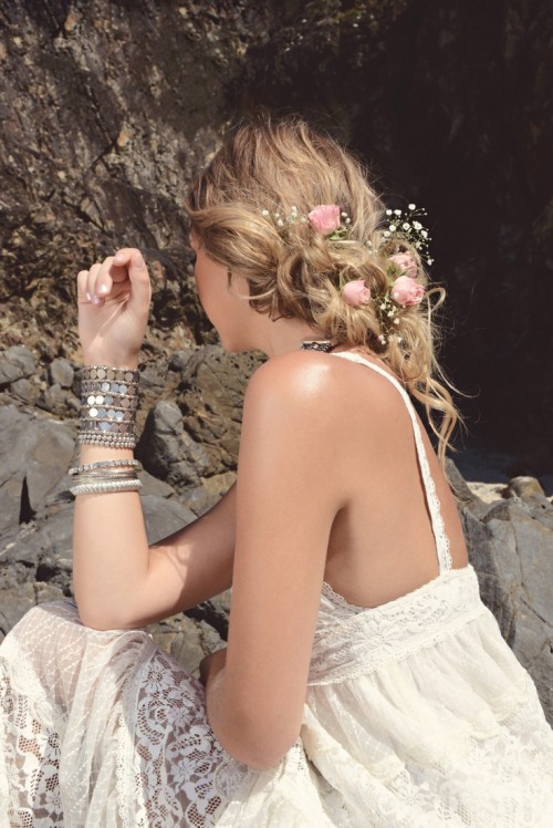 a messy boho chic low updo with twists and waves and fresh blooms, with a messy volume on top is a lovely idea to rock