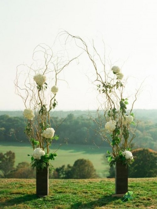 a spring wedding altar made of black vases and branch arrangements with greenery and white hydrangeas