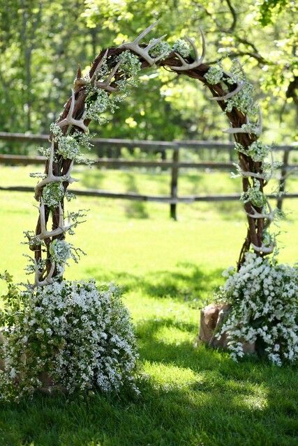 a woodland sprign wedding arch made of vine, with white blooms and greenery and lots of antlers