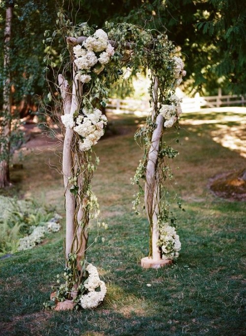 a spring wedding arch of branches and twigs plus white hydrangeas and some greenery