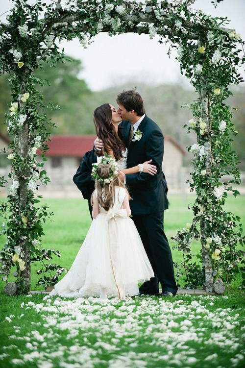 a simple and fresh spring wedding arch of greenery and some white blooms is all you need for a beautiful ceremony