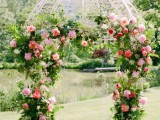 a lush and colorful sprign wedding arch done with greenery and pink blooms all over for a bright spring wedding