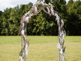 a refined wedding arch with vines, white fabric, greenery and white blooms for a spring wedding