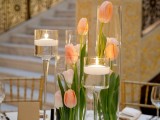 glass vases with peachy tulips and tall candleholders with floating candles for pure elegance and chic