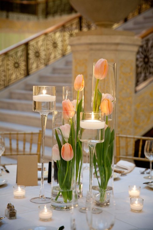 glass vases with peachy tulips and tall candleholders with floating candles for pure elegance and chic