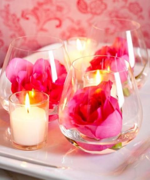 glasses with pink roses and candles around for a bright and lovely wedding centerpiece at Valentine's Day
