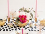 a glam wedding centerpiece of a gold bowl with white and fuchsia blooms and greenery plus pink candles in gold candleholders