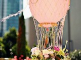 a cute Valentine’s Day wedding centerpiece styled as a hot air balloon – in pink, with greenery and pink blooms is very chic