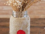 a jar with a burlap wrap with a heart and some dried blooms is a pretty rustic Valentine’s Day centerpiece