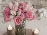a refined Valentine’s Day wedding centerpiece of a jar with pink and light pink roses and candles around always works