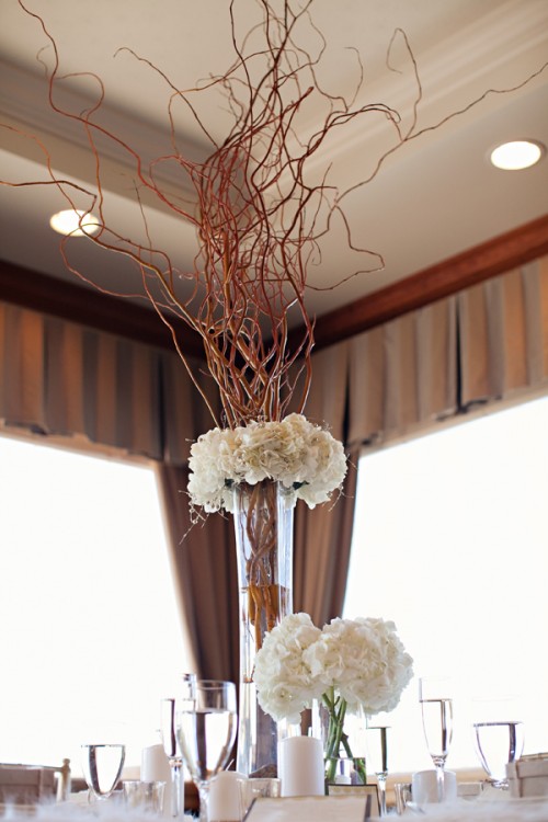 an elegant and formal winter wedding centerpiece of white blooms and tall branches in a vase