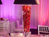 a unique winter wedding centerpiece of a lamp with red blooms floating inside it