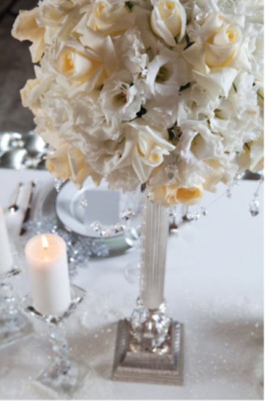 An elegant and formal white bloom centerpiece with pillar candles is a stylish idea to try
