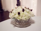 a rustic and cozy winter wedding centerpiece of white blooms, twigs and pinecones in a large vase