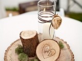 a rustic winter wedding centerpiece of a wood slice, a wood stump, a burnt wood slice and a candle with a fabric bloom