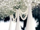 a white winter wedding centerpiece of bottles, baby’s breath and pearl strands for a chic look