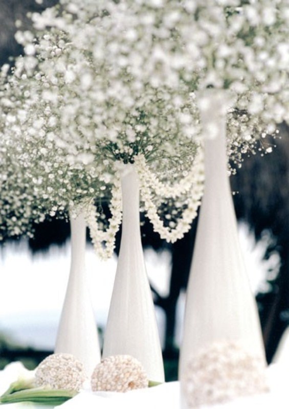 A white winter wedding centerpiece of bottles, baby's breath and pearl strands for a chic look