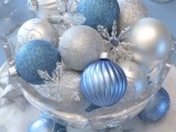 a blue and silver winter wedding centerpiece of ornaments in a glass bowl and snowflakes is easy to compose