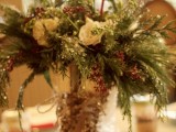 a creative winter wedding centerpiece of glitter skates with a lush evergreen, white bloom floral arrangement plus a chalkboard table number