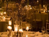 a stylish winter wedding centerpiece of glasses with pinecones inside and soem floating candles on top