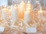 an elegant winter wedding centerpiece of white pillar candles and white petals will also fit other seasons as well
