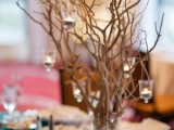 a unique winter wedding centerpiece of branches, glitter in the vase, some hanging candles