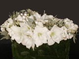 a formal winter wedding centerpiece of a bowl with evergreens, white blooms and large beads