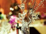 a frozen winter wedding centerpiece of branches and some candles hanging on them is a stylish and simple idea