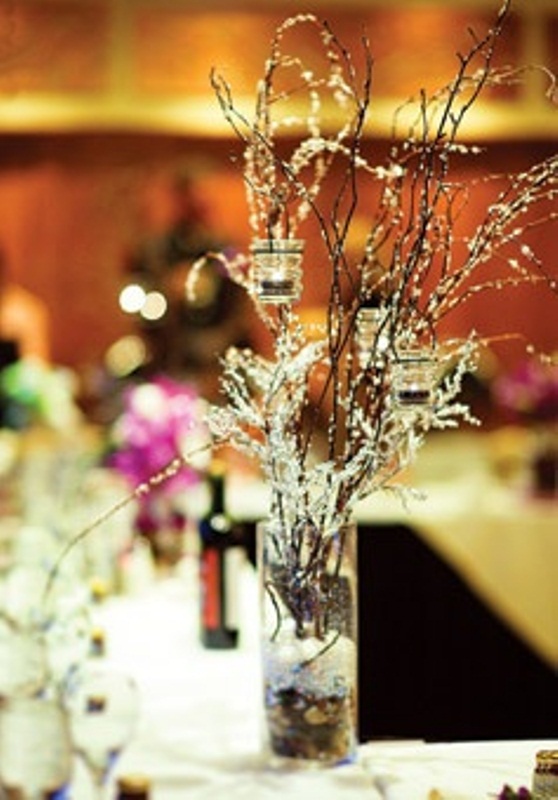 A frozen winter wedding centerpiece of branches and some candles hanging on them is a stylish and simple idea
