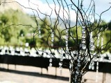 a stylish winter wedding centerpiece of black branches and crystals hanging gown from them