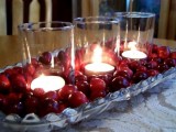 a gorgeous winter wedding centerpiece of a bowl withcranberries and candles in candleholders