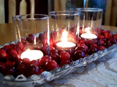a gorgeous winter wedding centerpiece of a bowl withcranberries and candles in candleholders
