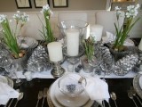 a winter wedding centerpiece of silver pinecones, white blooms, snowy pinecones and pillar candles