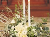 a white and green floral centerpiece with tall and thin candles is a stylish idea for a winter wedding