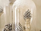 snowy pinecones in gold stands and in a snowy cloche on top is a stylish idea for a winter wedding