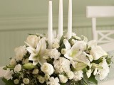 a refined winter wedding centerpiece of blooms and three thin and tall candles