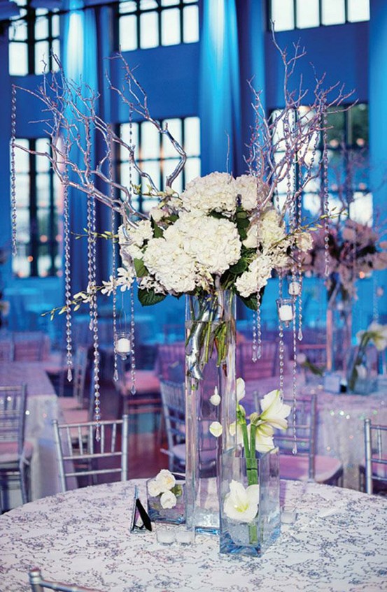 A winter wedding centerpiece of white blooms, with branches with crystals hanging down