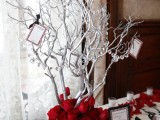 a winter centerpiece of silver branches with crystals and red roses looks dramatic and will fit a winter wonderland wedding