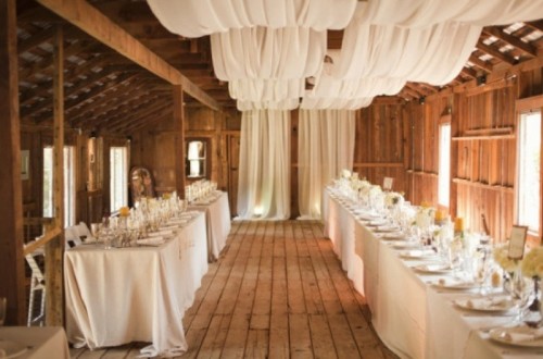a rustic barn wedding reception space with neutral linens, blooms and cards