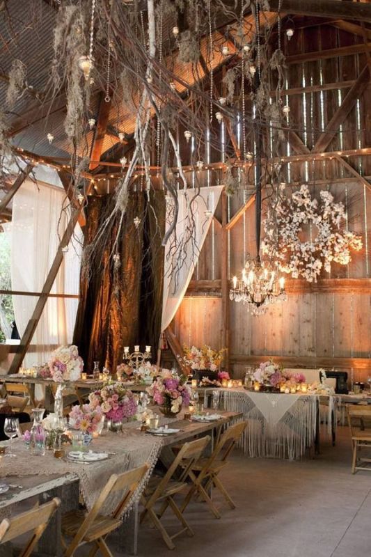 a whitewashed wedding reception space with white blooms, linens, branches, crystals, candles and pink blooms