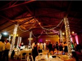 a barn wedding reception space with lights and neutral linens is a stylish and cozy space