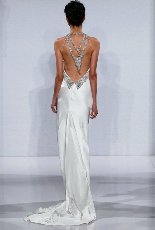a modern fitting wedding dress of plain fabric, with an open back and heavy embellishments hanging down on this back is gorgeous