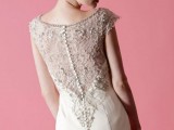 a refined fitting wedding dress wiht an illusion back of lace, rhinestones and a row of buttons, with cap sleeves and a high neckline