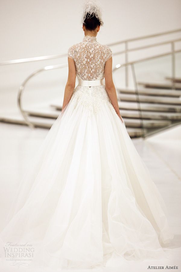 A sophisticated A line wedding dress with a lace applique illusion back, a high neckline and cap sleeves and a plain full skirt with a train is beautiful